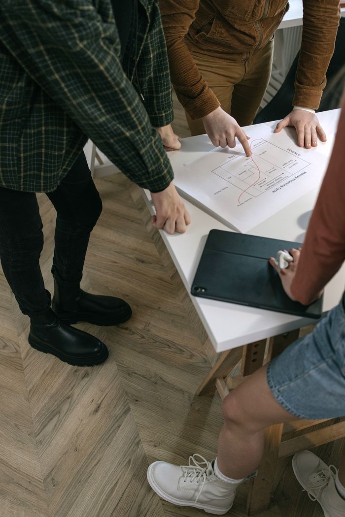 our-story Top view of a team brainstorming at a desk with a chart, showcasing teamwork and planning skills.